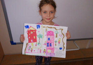 Dziewczynka trzyma w rękach swój rysunek